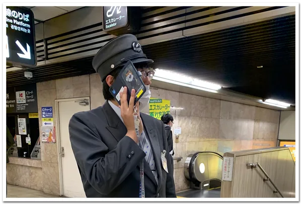 駅構内でスマートフォンを使って通話する職員